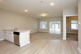 This single-floor unit offers a clean, contemporary design with a neutral color palette throughout. The open-concept kitchen serves as a functional centerpiece, featuring white cabinetry, granite-look countertops, and a full suite of stainless steel appliances including a refrigerator, electric range, and over-the-range microwave. A peninsula with an integrated sink and breakfast bar creates a natural division between the kitchen and the adjacent living area, with light hardwood-style flooring extending throughout the kitchen space.

The living area is generously sized, finished with plush neutral carpeting that continues into the bedroom. Large windows and a sliding glass door with vertical blinds allow natural light to fill the space and provide access to the outdoors. The bedroom features the same soft carpeting, neutral wall tones, and a closet with built-in shelving for organized storage.

The bathroom is well-appointed with a white vanity, granite-look countertop, a large mirror, a tub-shower combination, and matching light hardwood-style flooring. Clean white trim and recessed lighting throughout the unit contribute to a bright, cohesive aesthetic. The 3D floor plan confirms an efficient, well-organized layout designed for comfortable everyday living.