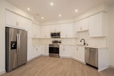 Located at 15052 Brookhurst St in Westminster, California, this single-story unit offers a thoughtfully updated interior with a clean, neutral aesthetic throughout. The standout feature is the fully renovated kitchen, which is designed for both functionality and style. Crisp white shaker-style cabinetry lines the walls from floor to ceiling, providing generous storage space, while light-toned quartz countertops and a classic white subway tile backsplash contribute to a bright, modern look. Gold-toned hardware adds a warm contrast to the all-white palette. The kitchen is equipped with a full suite of stainless steel appliances, including a French door refrigerator with an ice and water dispenser, a freestanding electric range, an over-the-range microwave, and a dishwasher. Light wood-look flooring runs through the kitchen and living areas, lending warmth to the space. The bedroom features plush wall-to-wall carpeting and a closet, creating a comfortable and private retreat. The bathroom is finished with light flooring, a full soaking tub and shower combination, matte black fixtures and hardware, and recessed lighting. The overall interior presents a freshly updated, move-in-ready environment with a consistent, neutral color scheme throughout.