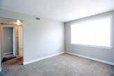 Located at 7703 Major Ave in Norfolk, Virginia, this single-floor residence offers a practical and comfortable layout with well-defined living spaces throughout. The living area is generously sized, featuring neutral-toned carpet, clean white baseboards, and soft gray walls that create a calm, understated atmosphere. Large windows allow natural light to fill the room, enhancing the open feel of the space.

The kitchen is compact yet efficiently arranged, equipped with a gas range, a double-basin stainless steel sink, and ample upper and lower cabinetry featuring wood-trimmed white finishes. A window above the sink brings in additional natural light, and durable tile flooring completes the practical design.

The bedrooms are carpeted and well-proportioned, each featuring neutral walls, windows with blinds, and good closet storage. One bedroom notably includes access to a bathroom and benefits from multiple closets, offering added convenience and storage capacity.

The bathroom features classic floor-to-ceiling tile work in a cream and black accent scheme, a full soaking tub, and a window that provides ventilation and natural light. The overall aesthetic throughout the residence is clean, neutral, and move-in ready, making it a functional and straightforward living space in the Norfolk area.