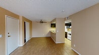 This efficiently designed single-floor residence offers a thoughtful layout across one bedroom and one bathroom. The open living and dining area is finished with warm-toned diagonal tile flooring and features a ceiling fan with light fixture, creating a functional and comfortable space. Neutral beige walls throughout lend a cohesive, understated aesthetic to the entire unit.

The kitchen is positioned adjacent to the dining area and is accessible via a pass-through countertop with a granite-style surface that also serves as a breakfast bar. Dark espresso cabinetry contrasts with white appliances, including a refrigerator and range, while overhead ventilation keeps the space practical. The kitchen's open sightlines into the main living area enhance the sense of openness.

The bedroom offers a comfortable footprint, carpeted flooring, a ceiling fan, and a window with vertical blinds that allows natural light to filter in and provides views of what appears to be an outdoor pool area. A closet with bi-fold doors offers convenient storage.

The bathroom includes a granite-topped vanity with a dark-framed mirror, tile flooring, and a tiled shower enclosure, combining function with clean, classic finishes throughout.