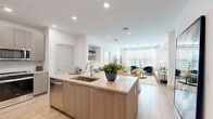 Located at 99 Wilkens Lane in Barnstable, MA, this thoughtfully designed two-bedroom, two-bathroom residence offers a seamless single-floor layout with modern finishes throughout. The open-concept kitchen and living area serves as the heart of the home, anchored by a sleek kitchen island with quartz countertops, warm wood-toned cabinetry, stainless steel appliances including a range and built-in microwave, and a subway tile backsplash. The island accommodates bar seating, making it ideal for casual dining or entertaining. The living room flows naturally from the kitchen, featuring recessed lighting, light hardwood-style flooring, and large windows dressed with white blinds and curtains that invite abundant natural light. The primary bedroom is a well-proportioned retreat with large windows and access to a dedicated closet. The primary bathroom is finished with large-format marble-style tile flooring, a soaking tub with shower, a floating wood vanity, and wall-mounted lighting. The second bedroom is bright and airy, also benefiting from natural light and closet space. Throughout the residence, a clean, neutral palette of whites and warm wood tones creates a cohesive and contemporary ambiance suited to a variety of lifestyles.