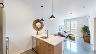 Located at 5077 N Broadway Street in Chicago's vibrant Edgewater neighborhood, this single-floor residence combines contemporary design with functional living. Polished concrete floors run throughout the main areas, lending a sleek, industrial-modern aesthetic that ties the space together cohesively.

The open-concept kitchen is a standout feature, equipped with stainless steel appliances including a gas range, microwave, and refrigerator. Warm wood cabinetry is paired with crisp white upper cabinets and a classic subway tile backsplash. A generous peninsula with a quartz countertop, undermount sink, and matte black faucet provides seating for several bar stools, making it ideal for casual dining and entertaining. Pendant lighting in a matte black finish adds a modern accent above the peninsula.

The living area is bright and welcoming, with large floor-to-ceiling windows and a glass door that flood the room with natural light and offer views of the surrounding streetscape. A wall-mounted mini-split system ensures year-round comfort.

The bedroom continues the airy feel with generous window access and views of the neighborhood below. The bathroom features a clean, minimalist design with a white vanity, polished concrete flooring, and a glass-enclosed shower. A dedicated built-in desk nook provides a practical workspace, completing this well-appointed urban residence.