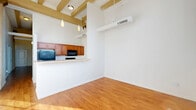 Located at 1010 Central Ave in Indianapolis, this two-bedroom, two-bathroom residence offers a thoughtfully designed single-floor layout with standout architectural character. The open-concept living and kitchen area immediately impresses with soaring ceilings accented by exposed wood beams and warm hardwood-style flooring throughout. Pendant lighting adds a modern touch, while the raised breakfast bar separates the kitchen from the living space, creating a functional yet connected flow. The kitchen is well-equipped with warm-toned cabinetry, a full suite of black appliances including a refrigerator, electric range, built-in microwave, and dishwasher, along with ample counter and storage space on both sides of the galley-style layout. A wide hallway with continued beam detailing connects the living area to the private quarters, where two carpeted bedrooms offer comfortable retreats with high ceilings. The spacious primary bedroom includes a private en-suite bathroom and a walk-in closet with wire shelving. Both bathrooms feature tub/shower combos with white tile surrounds and hardwood-style flooring. Three closets total and a dedicated laundry area round out the practical amenities of this well-appointed home.