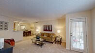 Located at 100 Lakeshore Crossing NE in Atlanta, Georgia, this single-floor, three-bedroom, two-bathroom residence offers a well-organized layout with comfortable living spaces throughout. The carpeted living room is bright and welcoming, featuring a door with slatted blinds that opens to a private outdoor area, allowing natural light to filter in. The space flows seamlessly into a dedicated dining area, accented by wainscoting and neutral walls, which connects directly to the galley-style kitchen. The kitchen is well-appointed with warm wood cabinetry, granite-style countertops, tile flooring, track lighting, and a full suite of black appliances including a range, microwave, refrigerator, and dishwasher. The primary bedroom is a comfortable retreat with plush carpet, a ceiling fan, and natural light from a window with sheer curtains. The additional bedrooms are similarly finished with soft carpet and ceiling fans. The bathrooms include a clean, glass-enclosed walk-in shower. Two closets provide ample storage throughout the home. The overall aesthetic is warm and neutral, with consistent finishes that create a cohesive and inviting atmosphere across all rooms.