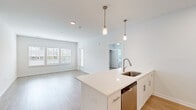 Located at 44000 Owl Wood Lane in Summerville, SC, this well-designed 2-bedroom, 3-bathroom single-story home offers a clean, modern aesthetic throughout. The open-concept kitchen and living area serves as the heart of the home, featuring light wood-look flooring, crisp white walls, and an abundance of natural light from multiple windows with blinds. The kitchen is outfitted with white shaker-style cabinetry, quartz countertops, a stainless steel undermount sink, and a full suite of stainless steel appliances including a refrigerator, range, microwave, and dishwasher. Pendant lighting above the kitchen island adds a contemporary touch. The living area provides a bright, airy atmosphere with a private entry door and large windows overlooking the outdoors. Both bedrooms feature plush carpet flooring, ceiling fans, and windows that bring in natural light. The generously sized primary bedroom includes access to a closet. The bathrooms are finished in a clean, neutral palette; one features a full tub-shower combination with classic white subway tile surround and chrome fixtures. Two dedicated closets provide ample storage. The home's consistent use of light tones and modern finishes creates a cohesive, inviting atmosphere throughout.