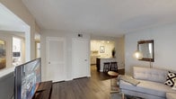 This single-floor residence offers a thoughtfully designed layout that balances functionality and contemporary style. The living area serves as the heart of the home, featuring dark hardwood-style flooring, a textured ceiling, and an open sightline toward the kitchen. A louvered storage closet and an additional door provide convenient utility access directly from the main living space.

The kitchen is outfitted with light wood cabinetry extending to the ceiling for ample storage, stone-look countertops, stainless steel appliances including a range and over-the-range microwave, and track lighting overhead. A raised breakfast bar with dark wood barstool seating connects the kitchen to the living area, enhancing the open flow.

The bedrooms feature hardwood-style flooring, neutral wall tones, and windows fitted with horizontal blinds that allow controlled natural light. Closet access is conveniently integrated into each room.

The bathrooms are clean and functional, each featuring a tub-shower combination with a curved curtain rod, stone-look vanity countertops, wood cabinetry, and hardwood-style flooring. Overall, the residence presents a cohesive, modern aesthetic with warm neutral tones throughout.