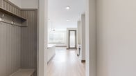 This well-appointed single-floor residence offers a clean, contemporary design throughout its thoughtfully laid-out living spaces. The open-concept kitchen and living area serves as the heart of the home, featuring light hardwood-style flooring, recessed lighting, and a ceiling fan that enhances the airy ambiance. The kitchen is outfitted with white shaker cabinetry, a light stone countertop island with an undermount sink, a tile backsplash, stainless steel appliances including a refrigerator and microwave, and a built-in beverage cooler. Elegant glass globe pendant lights illuminate the island, adding a refined touch. The adjacent living area benefits from abundant natural light streaming through large windows dressed with horizontal blinds, and a glass-panel exterior door provides an inviting connection to the outdoors. The bedrooms feature plush carpeting, ceiling fans, and generous walk-in closets with built-in shelving. The full bathroom is finished with a dual-sink vanity topped with light stone counters, white cabinetry with brushed nickel hardware, framed mirrors, and a tiled tub-shower combination. A dedicated in-unit laundry area completes this thoughtfully designed residence, offering practicality alongside its modern aesthetic.