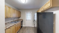 Located at 1940 Atlanta Rd SE in Smyrna, Georgia, this single-floor, 2-bedroom, 1-bathroom home offers a practical and comfortable layout with a cohesive neutral palette throughout. The living room serves as the heart of the home, finished with plush wall-to-wall carpeting and a ceiling fan overhead. A pass-through window with a granite-style counter connects the living area to the kitchen, creating an open and airy feel between the two spaces. The kitchen is well-appointed with warm honey-toned wood cabinetry, granite-look countertops, a stainless steel sink, a dishwasher, and a black refrigerator. Wood-look plank flooring adds durability and style, and a windowed back door fills the space with natural light. Both bedrooms feature soft carpeting, natural light from windows with blinds, and wall-mounted mini-split units for individualized climate control. The primary bedroom also includes a ceiling fan and closet access. The bathroom offers a full-size tub and shower combination with white tile surround and a window for ventilation. Throughout the home, neutral gray walls and clean white trim create a simple, move-in-ready atmosphere suited for comfortable everyday living.