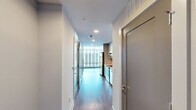 Located in the heart of downtown Raleigh on Fayetteville Street, this high-rise unit offers a sleek, modern living experience with sweeping city views. The open layout encompasses a living room, bedroom, bathroom, and hallway, all finished with light-toned hardwood-style flooring and crisp white walls that create a bright, clean aesthetic throughout.

The living room is a standout space, defined by dramatic floor-to-ceiling glass curtain walls fitted with horizontal blinds, framing panoramic views of the Raleigh skyline and filling the room with abundant natural light. The airy, open feel makes the space ideal for both relaxing and entertaining.

The bedroom continues the modern design language with the same hardwood-style flooring, a ceiling fan with integrated lighting, and a double-door closet offering practical storage. Clean lines and neutral tones keep the room feeling calm and versatile.

The bathroom is elegantly appointed with a walk-in glass-enclosed shower featuring gold-toned hardware and large-format tile surround, complemented by a single vanity with a white quartz countertop, wood-grain cabinetry, and recessed and vanity lighting. The tile flooring ties the refined look together seamlessly.

This unit delivers a polished urban living experience in one of Raleigh's most central locations.