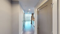 Located in the heart of downtown Raleigh on Fayetteville Street, this high-rise unit offers a sleek, modern living experience with sweeping city views. The open layout encompasses a living room, bedroom, bathroom, and hallway, all finished with light-toned hardwood-style flooring and crisp white walls that create a bright, clean aesthetic throughout.

The living room is a standout space, defined by dramatic floor-to-ceiling glass curtain walls fitted with horizontal blinds, framing panoramic views of the Raleigh skyline and filling the room with abundant natural light. The airy, open feel makes the space ideal for both relaxing and entertaining.

The bedroom continues the modern design language with the same hardwood-style flooring, a ceiling fan with integrated lighting, and a double-door closet offering practical storage. Clean lines and neutral tones keep the room feeling calm and versatile.

The bathroom is elegantly appointed with a walk-in glass-enclosed shower featuring gold-toned hardware and large-format tile surround, complemented by a single vanity with a white quartz countertop, wood-grain cabinetry, and recessed and vanity lighting. The tile flooring ties the refined look together seamlessly.

This unit delivers a polished urban living experience in one of Raleigh's most central locations.