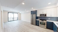 Located in the vibrant East Hollywood neighborhood of Los Angeles, this modern single-floor residence at 1111 N Kenmore Ave offers a thoughtfully designed open-concept layout finished with light-toned hardwood flooring throughout. The living area is generously proportioned, bathed in natural light, and opens directly to a private balcony through a full-width sliding glass door, providing a seamless indoor-outdoor connection.

The kitchen is a standout feature, showcasing a striking two-tone design with navy blue lower cabinets paired with crisp white upper cabinetry. A textured blue tile backsplash complements the stainless steel appliance suite, which includes a French door refrigerator, gas range, built-in microwave, and dishwasher. White quartz countertops and a stainless steel sink complete the functional and stylish workspace.

The bedroom is a bright, tranquil retreat with black-framed windows that allow ample natural light and include a dedicated walk-in closet for generous storage. Recessed lighting throughout the unit maintains a clean, contemporary aesthetic.

The bathroom features a full soaking tub and shower combination accented by floor-to-ceiling marble-effect tile, complemented by neutral floor tiling and crisp white walls, creating a clean and modern feel.