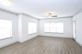 This single-floor residence offers a thoughtfully designed open-concept layout connecting the main living and kitchen areas. The kitchen is a functional centerpiece, showcasing dark espresso cabinetry, granite countertops, a subway tile backsplash, and stainless steel appliances including a range, microwave, and refrigerator. A central island with pendant lighting above provides additional prep space and serves as a natural divider between the kitchen and the adjacent living area. Light wood-look flooring runs throughout the main living spaces, complemented by multiple windows fitted with horizontal blinds that allow ample natural light.

The living area is generously sized with crown molding detail, a ceiling fan, and multiple windows that enhance the bright, airy atmosphere. The bedroom features plush carpeting, a ceiling fan, and a walk-in closet with built-in shelving. A second carpeted room, also equipped with a ceiling fan and a large window, offers flexible use as an additional bedroom or office. The bathroom is finished with light wood flooring, a glass-enclosed tile shower, a dark vanity with white countertop, and chrome fixtures, maintaining a clean and contemporary aesthetic throughout.