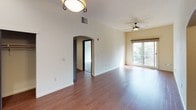 This single-floor 2-bedroom, 2-bathroom residence features a cohesive design with warm wood-look flooring throughout the main living areas and plush carpet in the bedrooms. The open living and dining area is highlighted by soaring ceilings, an elegant arched entryway, and a ceiling fan, with a sliding glass door that fills the space with natural light and provides access to an outdoor balcony. The kitchen is well-equipped with dark espresso cabinetry, granite-style countertops, stainless steel appliances including a range, microwave, and dishwasher, along with a full-size refrigerator. An in-unit laundry area is conveniently accessible from the main living space. Both bedrooms offer carpeted floors, neutral toned walls, and natural light from windows with views of surrounding greenery. The two bathrooms are finished with dark vanity cabinetry, granite-style countertops, and wood-look flooring. The primary bathroom includes a dual-sink vanity and a tub-shower combination with sliding glass doors, while the secondary bathroom features a single vanity with stylish light fixtures. Dark-stained interior doors with arched paneling add a distinctive architectural touch throughout the unit.