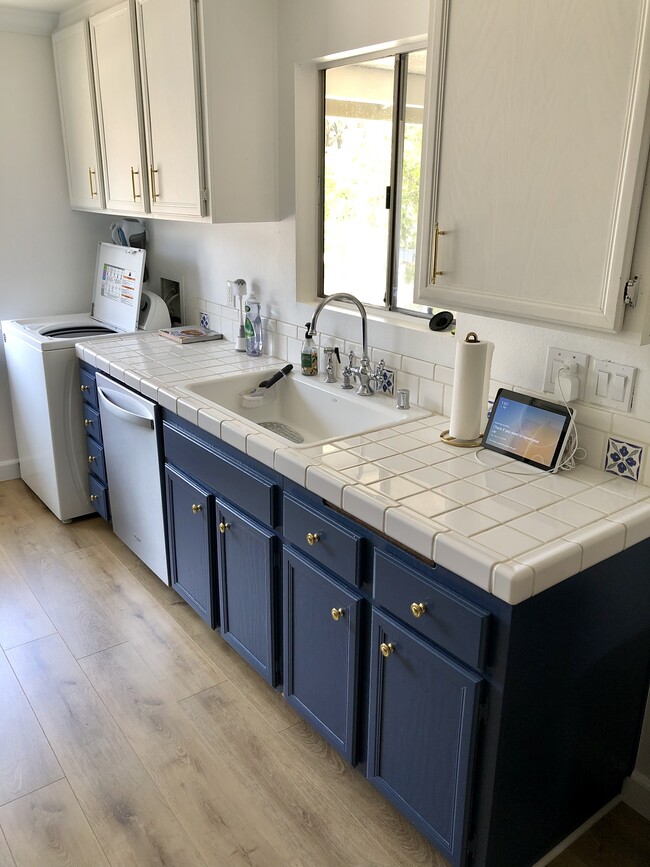 Upper cabinets are painted white while the lowers are blue with polished brass hardware. - 23705 Sea Breeze Ln