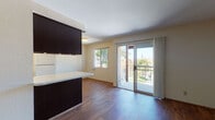 Located at 1515 Broadway in El Cajon, California, this single-floor unit offers a practical and well-appointed layout with consistent wood-style flooring flowing throughout every room, creating a warm and cohesive aesthetic.

The living area is bright and open, anchored by a sliding glass door that leads to a private balcony with an iron railing and tree-lined views of the surrounding neighborhood. A window alongside the door further enhances natural light, giving the space an airy feel.

The kitchen is efficiently designed in a galley configuration, featuring rich dark cabinetry that extends to the ceiling for ample storage, white appliances including a refrigerator, range, and dishwasher, and a recessed light fixture overhead. A light-toned countertop provides contrast against the dark cabinetry, adding visual interest.

The bedroom offers a clean, neutral environment with soft gray-toned walls and a sliding door closet, providing functional storage. The entry area is spacious and straightforward, with a solid front door and good flow into the main living spaces.

The bathroom is accessed via a hallway and features a dark-cabineted vanity with a white countertop and sink, a large mirror, and matching wood-style flooring that maintains design continuity throughout the unit. The overall ambiance is clean, neutral, and move-in ready.