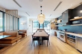 Located at 1081 Juniper St NE in Atlanta's Midtown neighborhood, this thoughtfully designed Social Kitchen is a shared culinary and gathering space that seamlessly blends function with contemporary style. Light hardwood flooring flows throughout, lending warmth and continuity to the open-concept layout.

At the heart of the space is a generously sized communal dining table topped with a natural wood surface, illuminated by a striking cluster of geometric pendant lights. The fully equipped gourmet kitchen lines the back wall and is anchored by a professional-grade stainless steel range, built-in dishwasher, and a full-size refrigerator. Deep teal subway tile backsplash adds a bold design statement, complemented by open wood shelving displaying ceramics and glassware. Light wood cabinetry with white countertops keeps the aesthetic clean and modern.

A private banquette nook, upholstered in warm cognac leather, sits adjacent to large floor-to-ceiling windows that flood the space with natural light and offer views of the surrounding urban greenery. A slim slatted partition elegantly defines this cozy seating area from the main dining zone. The space is accessed through sleek glass-and-steel doors, with "Social Kitchen" etched prominently on the glass — underscoring its communal purpose.