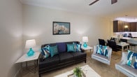 Located at 9511 Wes Kearney Way in Riverview, Florida, this single-floor residence offers a well-designed layout with a cohesive, neutral color palette throughout. The kitchen is a standout feature, showcasing rich dark cabinetry, light quartz countertops with under-cabinet LED accent lighting, stainless steel appliances including a refrigerator, range, and microwave, and a peninsula with bar seating — ideal for casual dining. Wood-look flooring and track lighting complete the space's modern aesthetic.

The living area is warm and inviting, featuring plush carpeting, crown molding, and a ceiling fan, creating a comfortable gathering space. Two well-proportioned bedrooms continue the soft, neutral tones with carpeted floors. The primary bedroom includes access to a dedicated walk-in closet with built-in shelving and hanging rods, offering generous storage. The second bedroom also benefits from a private closet.

The full bathroom is finished with a dark vanity, quartz countertop, and a tiled shower-tub combination. A dedicated in-unit laundry room with side-by-side washer and dryer hookups and wood-look flooring adds a practical and convenient amenity. Throughout the home, large windows invite natural light, contributing to the bright and airy atmosphere of this thoughtfully appointed residence.