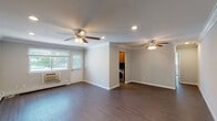 Located at Fairfield New England Village in Hauppauge, New York, this single-floor residence offers a well-designed layout with consistent, high-quality finishes throughout. Rich dark hardwood-style flooring flows across the main living areas, complemented by crisp white crown molding and neutral gray walls that create a clean, modern aesthetic.

The open living area is spacious and airy, featuring dual ceiling fans with light fixtures and recessed lighting. Natural light enters through multiple windows fitted with horizontal blinds, and an in-unit washer is conveniently accessible from the main living space.

The galley-style kitchen is efficiently designed, offering warm wood cabinetry, dark granite countertops, stainless steel appliances including an electric range with overhead microwave, and a window that brings in natural light. An in-unit laundry area with cabinetry above is neatly tucked adjacent to the kitchen.

The bedroom is generously sized, bathed in natural light from two windows, and equipped with a ceiling fan, recessed lighting, crown molding, and dual closets providing ample storage. The bathroom includes a tiled tub and shower combination with a glass door and a natural light window. Baseboard heating is present throughout, ensuring year-round comfort in this thoughtfully appointed residence.