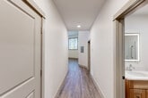 Located at 870 Westminster St in Providence, Rhode Island, this one-bedroom, one-bathroom unit offers a thoughtfully designed layout across a single floor. The open living and kitchen area immediately impresses with dramatically high ceilings that lend an expansive, airy feel to the space. Warm hardwood-style flooring flows consistently throughout, tying together each room with a cohesive, contemporary aesthetic.

The kitchen is well-appointed with light wood cabinetry, a white subway tile backsplash, stainless steel appliances including a range, microwave, dishwasher, and refrigerator, as well as a ceiling fan that serves the combined living area. Natural light enters through windows framed in neutral trim, enhancing the bright, clean atmosphere.

The hallways connect the living space to the private quarters, featuring recessed lighting and a flush, modern design. The generously sized bedroom accommodates comfortable furnishing arrangements and includes a ceiling fan and access to a dedicated closet. The full bathroom is finished with a wood-toned vanity, white countertop, and hardwood-style tile flooring, maintaining the unit's consistent design language. Clean white walls and neutral finishes throughout give this unit a move-in-ready, modern appeal.