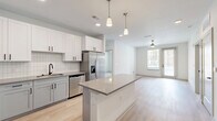 Located at 1148 N Main St in Jacksonville, FL, this well-appointed two-bedroom, two-bathroom residence offers a thoughtfully designed single-floor layout with a clean, contemporary aesthetic throughout. The open-concept living and kitchen area serves as the heart of the home, featuring light hardwood-style flooring, recessed lighting, and pendant lights over a central island with quartz countertops. The kitchen is fully equipped with stainless steel appliances — including a French door refrigerator, dishwasher, microwave, and range — complemented by shaker-style cabinetry and a classic subway tile backsplash. A ceiling fan anchors the living area, which receives natural light through large windows. Both bedrooms are carpeted and generously proportioned, each featuring a ceiling fan and windows with outdoor views of surrounding greenery. Two dedicated closets provide ample storage. The primary bathroom includes a double-sink vanity with gray cabinetry, a tub-shower combination with subway tile surround, and matte black fixtures. The second bathroom mirrors this modern style with a walk-in tiled shower and double vanity. The overall ambiance is bright, clean, and move-in ready.