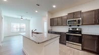 This single-floor residence showcases a thoughtfully designed open layout with consistent light wood-style flooring that flows seamlessly throughout the living areas. The kitchen serves as the heart of the home, centered around a spacious island with a granite countertop and integrated sink. Dark espresso-toned cabinetry lines the walls, complemented by a classic white subway tile backsplash and a full suite of stainless steel appliances, including a range, microwave, refrigerator, and dishwasher. Recessed lighting illuminates the kitchen and adjacent living area, while a ceiling fan adds comfort to the open-plan space.

The bedrooms are bright and airy, each featuring large windows dressed with horizontal blinds that allow natural light to filter in while maintaining privacy. The neutral wall tones and light flooring create a clean, versatile aesthetic throughout.

The bathrooms maintain the same design language as the rest of the unit, with dark-toned vanities topped with granite counters, light wood-style tile flooring, and tub-shower combinations fitted with brushed nickel fixtures. The overall ambiance of the space is modern, clean, and move-in ready, offering a cohesive and functional living environment.