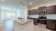 This single-floor residence showcases a thoughtfully designed open layout with consistent light wood-style flooring that flows seamlessly throughout the living areas. The kitchen serves as the heart of the home, centered around a spacious island with a granite countertop and integrated sink. Dark espresso-toned cabinetry lines the walls, complemented by a classic white subway tile backsplash and a full suite of stainless steel appliances, including a range, microwave, refrigerator, and dishwasher. Recessed lighting illuminates the kitchen and adjacent living area, while a ceiling fan adds comfort to the open-plan space.

The bedrooms are bright and airy, each featuring large windows dressed with horizontal blinds that allow natural light to filter in while maintaining privacy. The neutral wall tones and light flooring create a clean, versatile aesthetic throughout.

The bathrooms maintain the same design language as the rest of the unit, with dark-toned vanities topped with granite counters, light wood-style tile flooring, and tub-shower combinations fitted with brushed nickel fixtures. The overall ambiance of the space is modern, clean, and move-in ready, offering a cohesive and functional living environment.