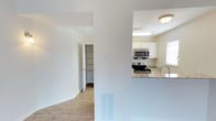Located at 955 Airport Rd in Destin, Florida, this single-story property offers a clean, functional layout designed for comfortable living. The interior features light hardwood-style flooring that flows throughout the main living areas, complementing the bright, neutral wall tones that give the space an open and airy feel. The kitchen is a standout feature, outfitted with white shaker-style cabinetry, granite countertops, and stainless steel appliances including an electric range and over-the-range microwave. A raised breakfast bar provides a convenient casual dining or workspace area, while a sink with a modern faucet adds practicality. Natural light filters in through windows, enhancing the freshness of the space. A dedicated walk-in storage closet or pantry area is accessible from the main corridor, offering generous organizational capacity. The layout is thoughtfully arranged to maximize flow between rooms, with wide doorways and a logical room sequence. Floor-mounted HVAC vents suggest a central air system for year-round climate control. The overall ambiance is tidy, modern, and move-in ready, well-suited for those seeking a low-maintenance property in the Destin area.