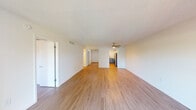 This single-floor unit is designed with a clean, functional layout that promotes an open and airy atmosphere throughout. Warm wood-look flooring extends consistently across all rooms, creating a cohesive and inviting feel. The main living area is generously proportioned, featuring a ceiling fan and a textured ceiling. Sliding glass doors open to an outdoor area, allowing abundant natural light to fill the space and providing pleasant views of surrounding greenery.

The kitchen is positioned adjacent to the living area and is equipped with stainless steel appliances, including a refrigerator, range with oven, and microwave. Two-toned cabinetry — white uppers and gray lowers — pairs with light countertops to create a modern aesthetic. The layout allows for easy flow between the kitchen and the main living space.

The bedrooms are well-sized and bright, each featuring wood-look flooring and windows that bring in natural light. One bedroom includes direct access to a bathroom with built-in vanity storage, as well as a closet with dedicated shelving. Additional rooms throughout the unit maintain the same neutral palette and consistent flooring, contributing to the overall clean and updated character of the space.