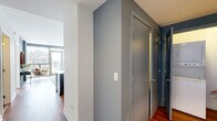 Located in Chicago's vibrant Old Town neighborhood, this one-bedroom, one-bathroom residence offers a well-designed layout across a single floor. Warm hardwood flooring flows throughout the main living areas, complementing the cool sage and steel-blue accent walls that lend the space a modern, cohesive aesthetic.

The open-concept kitchen and living room serve as the heart of the home. The kitchen is outfitted with rich dark-wood cabinetry, stainless steel appliances, and a generous white quartz island with bar seating — ideal for casual dining or entertaining. Pendant and track lighting highlight the space effectively. The living room is anchored by expansive floor-to-ceiling windows and a glass door leading to a private balcony, filling the room with natural light and offering sweeping views of the Chicago skyline.

The bedroom is a tranquil retreat, featuring large windows with continued city views, a blue accent wall, and a wide built-in closet providing ample storage. The full bathroom includes tile flooring, a tub-shower combination, and clean, functional finishes. A hallway connects the rooms efficiently, adding to the unit's practical flow. This residence combines contemporary design with an enviable location in one of Chicago's most sought-after neighborhoods.