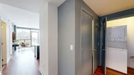 Located in Chicago's vibrant Old Town neighborhood, this one-bedroom, one-bathroom residence offers a well-designed layout across a single floor. Warm hardwood flooring flows throughout the main living areas, complementing the cool sage and steel-blue accent walls that lend the space a modern, cohesive aesthetic.

The open-concept kitchen and living room serve as the heart of the home. The kitchen is outfitted with rich dark-wood cabinetry, stainless steel appliances, and a generous white quartz island with bar seating — ideal for casual dining or entertaining. Pendant and track lighting highlight the space effectively. The living room is anchored by expansive floor-to-ceiling windows and a glass door leading to a private balcony, filling the room with natural light and offering sweeping views of the Chicago skyline.

The bedroom is a tranquil retreat, featuring large windows with continued city views, a blue accent wall, and a wide built-in closet providing ample storage. The full bathroom includes tile flooring, a tub-shower combination, and clean, functional finishes. A hallway connects the rooms efficiently, adding to the unit's practical flow. This residence combines contemporary design with an enviable location in one of Chicago's most sought-after neighborhoods.