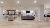 Located at 2 Walter Ave, this single-floor space showcases a thoughtfully designed open-concept layout that seamlessly connects multiple living and entertaining zones. Light wood-tone plank flooring runs throughout, lending a clean, contemporary feel to the entire space.

The central lounge area is anchored by a built-in entertainment wall finished in white, featuring a wall-mounted flat-screen TV, a sleek linear electric fireplace, and display shelving accented with decorative objects. Comfortable sectional and accent seating arrangements are positioned to take full advantage of this focal point.

Adjacent to the main lounge, a secondary seating area provides additional gathering space, with bold navy double doors serving as a striking architectural detail. Wall-mounted sconces and recessed lighting throughout ensure the space is well-lit and inviting.

A standout feature is the stylish wet bar, complete with a white quartz countertop, light wood cabinetry, a tile backsplash, floating shelves, gold-accented pendant lighting, and black leather bar stools with gold legs. A wall-mounted TV above the bar adds to its entertainment-ready appeal.

A large landscape mural adds a dramatic artistic element, while curated artwork and decorative accessories contribute to the space's polished, modern aesthetic. The open floor plan and generous proportions make this an ideal venue for both relaxed gatherings and lively entertaining.