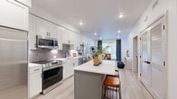 Located at 1090 W Hampden Ave in Englewood, Colorado, this thoughtfully designed one-bedroom, one-bathroom residence offers a bright and modern living experience across a single floor. The open-concept layout seamlessly connects the kitchen, dining area, and living room, creating an efficient and welcoming flow throughout the space.

The kitchen is a standout feature, showcasing white shaker-style cabinetry with matte black hardware, a grey subway tile backsplash, stainless steel appliances including a gas range, microwave, dishwasher, and side-by-side refrigerator. A central island with a crisp white countertop and bar seating serves as both a functional workspace and a casual gathering spot.

The living room is filled with natural light from a large window dressed with floor-length curtains, and features light wood-look flooring that extends throughout the entire residence, lending warmth and cohesion to the space.

The bedroom is a comfortable retreat, featuring a ceiling fan, large window with roller shades and decorative curtains, and a dedicated closet. The bathroom is finished in a clean, all-white palette with large-format tile flooring, a white vanity with black fixtures, and a well-lit mirror. Recessed lighting throughout reinforces the home's modern, polished aesthetic.
