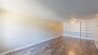 Located at 1969 Crystal Grove Dr in Lakeland, Florida, this single-story, three-bedroom, one-bathroom home offers a practical and well-organized layout. Wood-look flooring runs consistently throughout the entire home, lending a cohesive and clean aesthetic to every room.

The living room is a generously proportioned space highlighted by a textured ceiling, a ceiling fan with light fixture, and a wall of built-in open shelving that adds both character and functional storage. Natural light filters in through window treatments, creating a bright and welcoming atmosphere.

The kitchen is well-equipped with white cabinetry, dark countertops, a stainless steel sink, and a black electric range with overhead ventilation. The white cabinetry provides ample storage, and the layout allows for efficient use of the space.

Each of the three bedrooms features ceiling fans, textured ceilings, and wood-look flooring. The bedrooms are bright and comfortable, with windows allowing in natural light. Two bedrooms include closets, one of which features bifold doors for convenient access.

The full bathroom is finished in a clean, neutral palette with a white vanity, a tub-shower combination, and matching wood-look flooring. Additional features include two hallways, three closets, and a dedicated laundry area, rounding out the home's functional floor plan.