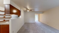 This single-floor, 1-bedroom, 1-bathroom unit offers a thoughtfully organized layout that maximizes functionality. The open living room is finished with plush wall-to-wall carpeting and features a ceiling fan with integrated lighting, creating a comfortable and well-ventilated space. A distinctive pass-through window connects the living area to the kitchen, enhancing the sense of openness between the two rooms.

The kitchen is equipped with warm-toned wood cabinetry, granite-look countertops, hardwood flooring, and includes a full-size refrigerator, electric range, and dishwasher — providing ample workspace and storage for everyday cooking.

The generously sized primary bedroom offers a notably spacious feel, with soft carpeting, a ceiling fan, a large window fitted with blinds for natural light and privacy, and a full-width sliding closet that provides substantial storage.

The bathroom features a wood vanity with granite-look countertops and hardwood flooring, connecting conveniently to the bedroom hallway. Throughout the unit, a neutral color palette of warm whites and beiges creates a clean, cohesive ambiance that is easy to personalize. The overall layout is efficient and practical, making effective use of every square foot.