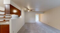 This single-floor, 1-bedroom, 1-bathroom unit offers a thoughtfully organized layout that maximizes functionality. The open living room is finished with plush wall-to-wall carpeting and features a ceiling fan with integrated lighting, creating a comfortable and well-ventilated space. A distinctive pass-through window connects the living area to the kitchen, enhancing the sense of openness between the two rooms.

The kitchen is equipped with warm-toned wood cabinetry, granite-look countertops, hardwood flooring, and includes a full-size refrigerator, electric range, and dishwasher — providing ample workspace and storage for everyday cooking.

The generously sized primary bedroom offers a notably spacious feel, with soft carpeting, a ceiling fan, a large window fitted with blinds for natural light and privacy, and a full-width sliding closet that provides substantial storage.

The bathroom features a wood vanity with granite-look countertops and hardwood flooring, connecting conveniently to the bedroom hallway. Throughout the unit, a neutral color palette of warm whites and beiges creates a clean, cohesive ambiance that is easy to personalize. The overall layout is efficient and practical, making effective use of every square foot.