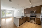 Located at 4400 Twain Ave in San Diego, CA, this single-floor residence offers a thoughtfully designed layout with contemporary finishes throughout. The open-concept kitchen serves as a central highlight, featuring rich wood-toned cabinetry, a tile mosaic backsplash, stainless steel appliances including a French door refrigerator, electric range, microwave, and dishwasher. A large island with a white quartz countertop and pendant lighting above adds both functionality and style. Light wood-style flooring extends through the main living areas, complementing the bright, neutral palette of the space.

The living area is well-proportioned, benefiting from natural light and track lighting overhead. Bedroom spaces are carpeted for comfort, each featuring blinds-covered windows that offer views of lush palm trees. One room provides direct outdoor access through a glass door, flooding the space with sunlight and greenery. A ceiling fan adds comfort to an additional bedroom.

The bathroom is finished with warm wood cabinetry, a broad vanity mirror, white quartz counters, and tile flooring. Adjacent to the bathroom is a generously sized walk-in closet outfitted with multi-level wire shelving, providing ample organized storage. Overall, the unit presents a clean, modern aesthetic with practical, well-considered details throughout.