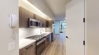 This 440 square foot studio apartment, located at 95 Wall Street in New York's Financial District, offers a blend of efficiency and luxury. The space is thoughtfully designed to maximize functionality within its compact footprint. The kitchen is a standout feature, boasting sleek wood-grain cabinetry, stainless steel appliances including a large refrigerator, built-in microwave, and gas range. Under-cabinet lighting illuminates the white backsplash and countertops, creating a bright workspace.

The bathroom exudes elegance with its marble-like tiling from floor to ceiling, a floating wood vanity, and a round mirror that adds a touch of modernity. The studio's main living area features warm wood flooring and neutral walls, providing a blank canvas for personalization. Large windows allow natural light to flood the space, enhancing the sense of openness.

Storage is cleverly integrated throughout, with ample closet space and overhead cabinetry in the kitchen. The apartment's layout, as seen in the 3D floor plan, demonstrates an efficient use of space, with clear delineation between living, sleeping, and functional areas. This Wall Street address combines urban convenience with upscale living, perfect for the discerning city dweller.