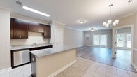 This well-appointed one-bedroom, one-bathroom residence in Weaverville, NC offers a thoughtfully designed single-floor layout that maximizes both function and comfort. The open-concept kitchen and living area serves as the heart of the home, where rich dark-espresso cabinetry pairs elegantly with granite countertops and a full suite of stainless steel appliances, including a refrigerator, range, and built-in microwave. A peninsula with matching granite provides additional prep space and casual seating. The kitchen transitions seamlessly into the living room, which features crown molding, a ceiling fan, and French doors that invite natural light and offer views to the outdoors. Light gray wood-style flooring flows throughout the main living areas, complemented by neutral warm-toned walls that create a clean, inviting atmosphere. The generously sized bedroom offers a calm retreat with ample room and direct access to a dedicated closet. The full bathroom is finished with tile flooring, a granite-topped dark vanity, and a tiled walk-in shower. A separate laundry room with wire shelving and full washer/dryer hookups adds everyday convenience, completing this functional and attractive residence.