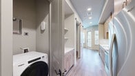 Located at 2080 FM 1102 in New Braunfels, TX, this thoughtfully designed one-bedroom, one-bathroom unit makes excellent use of its compact footprint. The galley-style kitchen is a standout feature, showcasing natural wood cabinetry, quartz countertops, a marble-look tile backsplash, a stainless steel sink with a matte black faucet, and a full suite of stainless steel appliances including a refrigerator, range, microwave, and dishwasher. Warm wood-look luxury vinyl plank flooring flows consistently throughout the living areas and bedroom, complemented by neutral gray walls that create a clean, contemporary feel. The bedroom is a calm, well-proportioned retreat featuring a high clerestory window that draws in natural light while maintaining privacy, along with recessed lighting and a ceiling fan. The bathroom is finished with large-format tile flooring, a wood-toned vanity with a white countertop, and direct access to a dedicated walk-in closet with built-in shelving and hanging rods. A barn-style sliding door adds a stylish architectural touch to the interior hallway. In-unit laundry is also included. Recessed lighting throughout ensures a bright, polished ambiance across every room.