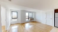 Located on the 10th floor in Astoria, Queens, this one-bedroom, one-bathroom residence offers an efficient and well-designed layout with a clean, modern aesthetic throughout. The living room is bright and airy, featuring warm hardwood flooring, crisp white walls, and large floor-to-ceiling windows that flood the space with natural light. A sliding glass door opens directly onto a spacious private terrace, where sweeping views of the Manhattan skyline and surrounding Queens neighborhood create a striking outdoor retreat. The kitchen is thoughtfully equipped with rich dark wood cabinetry, a tile backsplash, light stone countertops, stainless steel appliances including a gas range, microwave, dishwasher, and refrigerator, and recessed ceiling lighting. Light ceramic tile flooring completes the culinary space. The bedroom is a comfortable, well-proportioned room with the same warm hardwood floors, a large window offering open city views, and a wall-mounted HVAC unit. The bathroom features dark tile flooring, neutral wall tiling, a wood-toned vanity with an undermount sink, a framed mirror, and a bathtub. Throughout the unit, the design is clean and contemporary, making efficient use of its compact footprint.