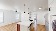 Located at 610 SE Moberly Ln in Bentonville, AR, this thoughtfully designed one-bedroom, one-bathroom home offers a clean, modern aesthetic with an efficient single-floor layout. Light oak-toned luxury vinyl plank flooring runs throughout, complementing the crisp white walls and creating a bright, cohesive feel.

The open-concept kitchen and living area serves as the heart of the home. The kitchen features white shaker cabinetry with matte black hardware, a white quartz waterfall island with a built-in black undermount sink, stainless steel appliances, and a stacked washer and dryer conveniently tucked nearby. A trio of sleek black pendant lights hang above the island, adding a striking design detail. The adjoining living area is generously proportioned and benefits from natural light through multiple windows.

The spacious primary bedroom accommodates a comfortable retreat, boasting two windows that allow ample natural light, warm flooring, and a ceiling fan. A dedicated closet provides practical storage.

The bathroom is finished with large-format white subway tiles surrounding a full soaking tub with an overhead shower, accented by matte black fixtures for a polished, contemporary look. The overall ambiance is clean, minimalist, and move-in ready.