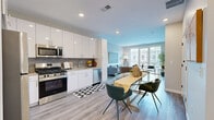 Located at 201 Munson Street in New Haven, CT, this well-appointed 2-bedroom, 2-bathroom residence offers a thoughtfully designed single-floor layout with modern finishes throughout. The open-concept living area seamlessly connects the kitchen, dining, and living spaces, all anchored by light wood-tone flooring and recessed lighting. The kitchen is outfitted with sleek white cabinetry extending to the ceiling, a gray tile backsplash, and a full suite of stainless steel appliances including a gas range, microwave, dishwasher, and refrigerator. The living room is bathed in natural light through large floor-to-ceiling windows and a glass door that frames neighborhood views, creating a bright and airy atmosphere. The generously sized primary bedroom features dual windows on adjacent walls, filling the room with natural light and offering outdoor views. The second bedroom also includes a large window with neighborhood views. Both bathrooms are finished with marble-look tile flooring, wood-toned vanities, white quartz countertops, and matte black fixtures. The residence includes two closets, one of which is a spacious walk-in with built-in wire shelving and hanging rods, providing ample storage. The neutral color palette and contemporary design create a clean, inviting ambiance throughout.