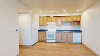 Located in Seattle's Broadview neighborhood, this single-story, three-bedroom, two-bathroom home offers a clean, modern design with a practical and efficient layout. Light wood laminate flooring flows consistently throughout, creating a bright and cohesive aesthetic across all rooms.

The kitchen is a functional centerpiece, featuring warm maple-toned cabinetry, blue-grey countertops, recessed lighting, and a full suite of white appliances including a refrigerator, electric range, and dishwasher. The open layout connects the kitchen to the living area, maximizing usability of the space.

The three bedrooms are well-proportioned and finished with neutral walls, natural wood window trim, and light flooring. The primary bedroom includes a ceiling fan, two windows with outdoor views of mature trees, and an adjacent closet with a full-length hanging rod. Additional bedrooms are similarly bright, each with natural light from windows fitted with blinds.

Two full bathrooms serve the home — one featuring a soaking tub and shower combination with a curved chrome rod, and a second with a single vanity, large mirror, and toilet. Both bathrooms are finished in a clean, neutral palette. Hallways connect the rooms efficiently, and a dedicated closet provides additional storage. The home presents a fresh, move-in ready condition throughout.