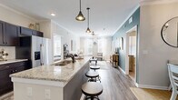 Located in Murfreesboro, TN, this single-story, 2-bedroom, 2-bathroom residence offers a thoughtfully designed open-concept layout that seamlessly connects the kitchen, dining, and living areas. The kitchen is a standout feature, boasting rich dark cabinetry, granite countertops, a subway tile backsplash, stainless steel appliances, and a large center island with bar seating and pendant lighting — ideal for both cooking and entertaining. Wood-look flooring flows throughout the main living areas, complemented by crown molding that adds a polished architectural detail. The living room is bright and welcoming, with multiple windows dressed in sheer curtains that invite natural light, along with a ceiling fan and neutral tones that create a relaxed, comfortable ambiance. A teal accent wall adds a touch of color and personality to the space. Both bedrooms are carpeted and well-lit with natural light from large windows, each equipped with ceiling fans. The primary bedroom connects to a private en-suite bathroom featuring dual granite vanities, dark cabinetry, and a tub-shower combination. A spacious walk-in closet with wire shelving provides ample storage. The second bathroom mirrors the same quality finishes. This residence combines modern style with functional living in a compact, efficient footprint.