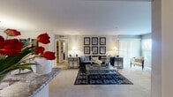This thoughtfully designed single-floor residence offers a seamless blend of comfort and modern style across a well-organized layout. The spacious living room serves as the heart of the home, anchored by a tiled fireplace with a classic mantel, large windows with vertical blinds that invite abundant natural light, and plush wall-to-wall carpeting underfoot. The open-concept flow connects the living area to a dedicated dining room, which features a pendant light fixture overhead and direct adjacency to the kitchen for convenient entertaining. The kitchen is outfitted with rich dark cabinetry, granite countertops, tile-look flooring, and stainless steel appliances including a range, microwave, refrigerator, and dishwasher. A dedicated laundry area provides full-sized washer and dryer units alongside a utility sink and additional closet storage. Two full bathrooms echo the home's refined aesthetic, each featuring granite-topped dark vanities, tile flooring, and tub or shower enclosures with stone-surround tiling. A hallway with closet storage connects the private areas of the home. Throughout, neutral tones and consistent finishes create a cohesive and inviting atmosphere well-suited to everyday living.