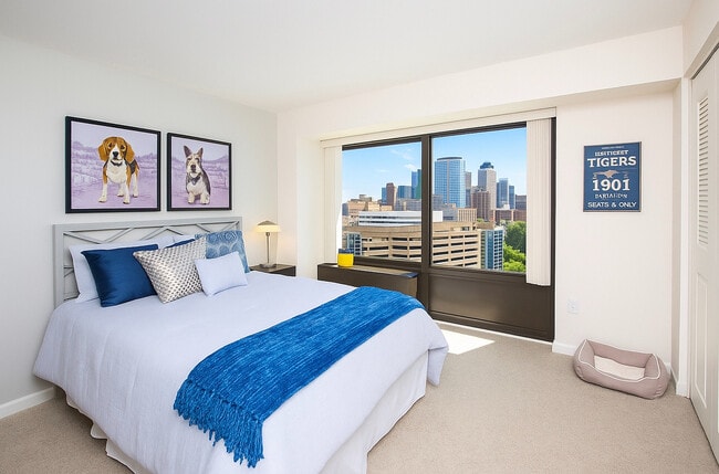 Dormitorio luminoso y acogedor con un diseño moderno, que cuenta con un gran ventanal con vistas al horizonte de la ciudad. - Riverfront Towers