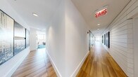 Located in Chicago's vibrant Old Town neighborhood, this thoughtfully designed amenity floor at 1225 N Wells St offers a generous and versatile layout spread across a single level. The space blends contemporary design with warm, inviting finishes throughout.

The gourmet kitchen is a standout feature, showcasing an oversized quartz island, sleek gray cabinetry, professional-grade stainless steel appliances, and a bold range hood. Exposed wood ceiling beams add warmth, while globe pendant lights provide stylish illumination.

The living areas are elegantly appointed with blue textured area rugs, modular seating, and distinctive vertical wood slat accent walls that divide zones with architectural flair. Floor-to-ceiling windows flood the space with natural light and frame sweeping panoramic views of the Chicago skyline and surrounding cityscape.

A dedicated games room features a full-size billiards table beneath an industrial pendant chandelier, a built-in fireplace with mounted TV, shiplap wall detailing, and additional seating areas bathed in natural light from wraparound windows.

Private glass-walled offices along the hallway offer transparency and a refined, professional aesthetic, with hardwood flooring and clean white interiors. The overall ambiance balances modern sophistication with comfortable communal living, making this an exceptional amenity destination.