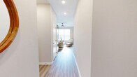 This thoughtfully designed single-floor home offers three bedrooms, two bathrooms, and a functional layout that maximizes every square foot. Light-toned walls and wood-look flooring run throughout, creating a cohesive, airy ambiance brightened by natural light streaming through slatted window blinds.

The open-concept living, dining, and kitchen area forms the heart of the home. The kitchen is a standout feature, equipped with rich dark-stained cabinetry, granite countertops, black appliances, and a large central island with seating — ideal for both cooking and casual dining. Pendant lighting adds a modern touch overhead. The dining area adjoins the kitchen and receives generous natural light.

The primary bedroom offers a comfortable retreat with direct access to an en-suite bathroom featuring a granite-topped vanity with dark cabinetry and a glass-enclosed walk-in shower with tile flooring. A dedicated walk-in closet with wire shelving provides ample storage.

The additional bedrooms are well-proportioned, with one featuring a large window with treetop views. The home also includes a dedicated laundry room, a hallway connecting the private quarters, a welcoming entrance, and four closets distributed throughout for abundant storage. A ceiling fan in the living area enhances comfort year-round.
