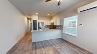 Located on Adventure Way in Colorado Springs, CO, this well-designed 2-bedroom, 2-bathroom single-floor home offers a functional and modern living experience. The open-concept living and kitchen area is anchored by a peninsula with a granite-style countertop, white cabinetry, a tile backsplash, and a full suite of stainless steel appliances including a refrigerator with ice maker, microwave, and range. Wood-look flooring runs throughout the main living areas, while recessed lighting and a ceiling fan add to the bright, comfortable atmosphere. Natural light filters in through blinds-covered windows, and a wall-mounted mini-split unit provides individual climate control. A dedicated laundry area with a stacked washer and dryer unit adds everyday convenience. Both bedrooms feature plush carpet flooring, windows with blinds, and individual wall-mounted climate control units, offering personal comfort in each room. The primary bedroom provides a generous layout with its own closet. Each bathroom is finished with a granite-style vanity countertop, white cabinetry, wood-look flooring, and a tub-shower combo. A hallway connects the bedrooms and bathrooms, with each room accessed through distinctive dark paneled doors, giving the home a cohesive, contemporary character throughout.