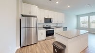Located at Bird Key Place in Palmetto, Florida, this one-bedroom, one-bathroom residence offers a thoughtfully designed layout that maximizes functionality and comfort. Light wood-look flooring flows consistently throughout, creating a cohesive and clean aesthetic.

The kitchen is a standout feature, showcasing white shaker-style cabinetry that extends to the ceiling, granite countertops, and a full suite of stainless steel appliances including a refrigerator, range, microwave, and dishwasher. A central island with a granite surface and built-in electrical outlets provides additional prep space and casual dining options. Recessed lighting illuminates the kitchen, and the open layout connects seamlessly to the rest of the living area.

The bedroom is a comfortable and airy retreat, featuring a ceiling fan, two windows that bring in ample natural light and views of the surrounding neighborhood, and a dedicated closet for organized storage.

The bathroom is well-appointed with white cabinetry, granite countertops, an undermount sink, and a tub-shower combination with white tile surround. A stacked washer and dryer unit is also present within the home, adding everyday convenience.

Overall, the space presents a modern, neutral palette with quality finishes throughout, making it a practical and inviting home in a Florida residential community.